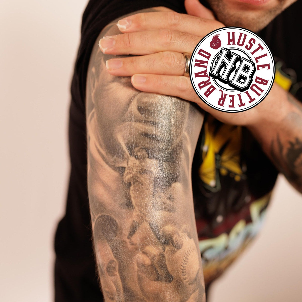 Man resting his hand on a forearm covered in a black and gray tattoo sleeve